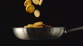 Slow Motion: Roasted Potatoes Fall Into A Steel Frying Pan On Black Background