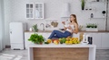 Happy Woman Eating Vegan Food. Modern Kitchen Background With Fresh Organic Food