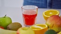 Glass Of Fresh Red Juice Among Fruits. Female's Hand Taking Glass