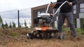 Gardener Loosens Soil With Walking Tractor In Urban Flower Beds. Gimbal Movement