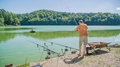 Man Swings Back The Fishing Rod And Throws Fish Feeder Far Into The Lake