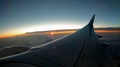 View From Airplane Window To Sunrise Or Sunset. Wing Of Plane Flying Above