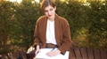 Short-Haired Girl With Notebooks And Abstracts In A Brown Coat. A Student Is