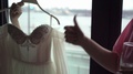 The Bride Is Holding A Wedding Dress, Preparing For Dressing. Bridesmaid Shows
