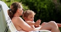 Mother Embracing Toddler Boy Outdoors In Swimming Pool Atmosphere. Family Enj