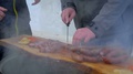Close Up Of A Man Chopping Slices Of Long Sausage On Wooden Log.
