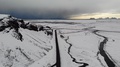 A Road Surrounded By Ice Heads Towards A Dark Storm In Iceland