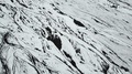 Abstract Aerial View Of Vehicle Moving On Snow Covered Black Lava Field In