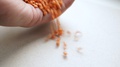 A Vegan Pours A Handful Of Raw Red Lentils From His Hand Onto A Table Or White