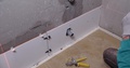 Builder Checks Correct Laying Of Ceramic Tiles In Bathroom With Large Level