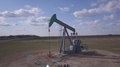 Pumpjack Pumps Oil On A Prairie Oilfield With Scattered Clouds Above