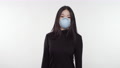 Young Woman Of Asian Decent Wearing A Medical Face Mask Gives A Peace Sign