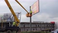 A Man Descends On A Lift. Posting Billboards. Crane