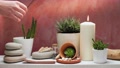 Hand Putting Down Scented Incense Stick On White Shelf With Candle, Rocks And