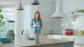 Internet Of Things Concept: Young Woman Using Smartphone In Kitchen.