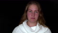 Sad Young Woman On A Black Background Looks At The Camera. The Clip Is