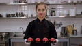 Pastry Chef Holds A Plate Of Strawberry-Shaped Mousse Cakes In A Pastry Kitchen.