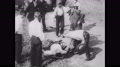 1930s Chicago: Man Crouches Down And Touches Man Laying On The Ground. Man