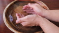 Man Puts His Hands In A Wooden Bowl Of Water And Grabs The Water In His Fists