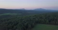 Serene Aerial Shot Of Bountiful Forests Nearby Fields Of Grass With Mountains O