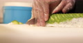 Hands With Disposable Plastic Gloves Carefully Slicing Sushi Rolls With