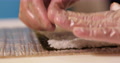Hands With Disposable Plastic Gloves Flattening Sushi Rice On Seaweed Wrap
