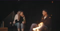 Happy Man And Woman Sitting By Camp Fire Drinking Beer Enjoying Adventure
