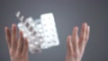 Caucasian Hands Throw Silver Blisters With Various Pills In Slow Motion