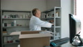Pharmacist Unpacking Delivery From Stock Indoor Of Drug Store Interior