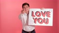 Handsome Guy Shows I Love You Sign To Camera Against Colourful Background