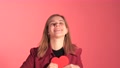 Cute Girl Points To Camera And Shows Red Paper Hart, In Love