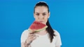 Portrait Of Pretty Young Woman Eating Watermelon Over Blue Background.