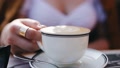 Young Blonde Woman Drinks Cappuccino Coffee In A Cafe Close-Up.
