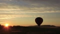 Colorful Rainbow Hot Air Balloon Slowly Ascends From Field Towards Sunrise 1