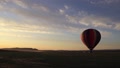 Colorful Rainbow Balloon Slowly Ascends From Field Towards Sunrise