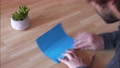 Timelapse, Man Folds And Unfolds Blue Origami Paper On Wooden Table