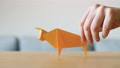 A Hand Moving Yellow Origami Ox On Table As Symbol For A Happy Chinese New Year.