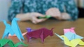 Colorful Origami Animals On Wooden Table. Hands In Background Folding Paper.