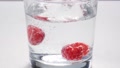 Raspberries Being Dropped Into Clear Fizzy Drink