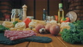 Raw Food On Wooden Table In Kitchen. Pasta, Eggs, Cheese, Vegetables, Cold Cuts
