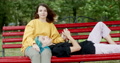 Two Loving Young Gay Women Relaxing On A Park Bench Holding Hands And Smiling