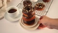 Doughnut On The Baking Rack Glazed With Chocolate Cream Or Icing. Woman Hand Put