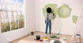 Young African American Female Alone Painting Wall With Roller Brush In Olive