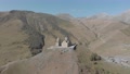 Aerial View Of Gergeti Trinity Monastery Up The Hill With Scenic Panorama Of