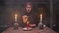 Senior Witch Woman Fortune Teller Moves Tarot Card Over Candle And Says Future