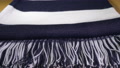 A Folded Dark Blue And White Striped Scarf With End Tassels.